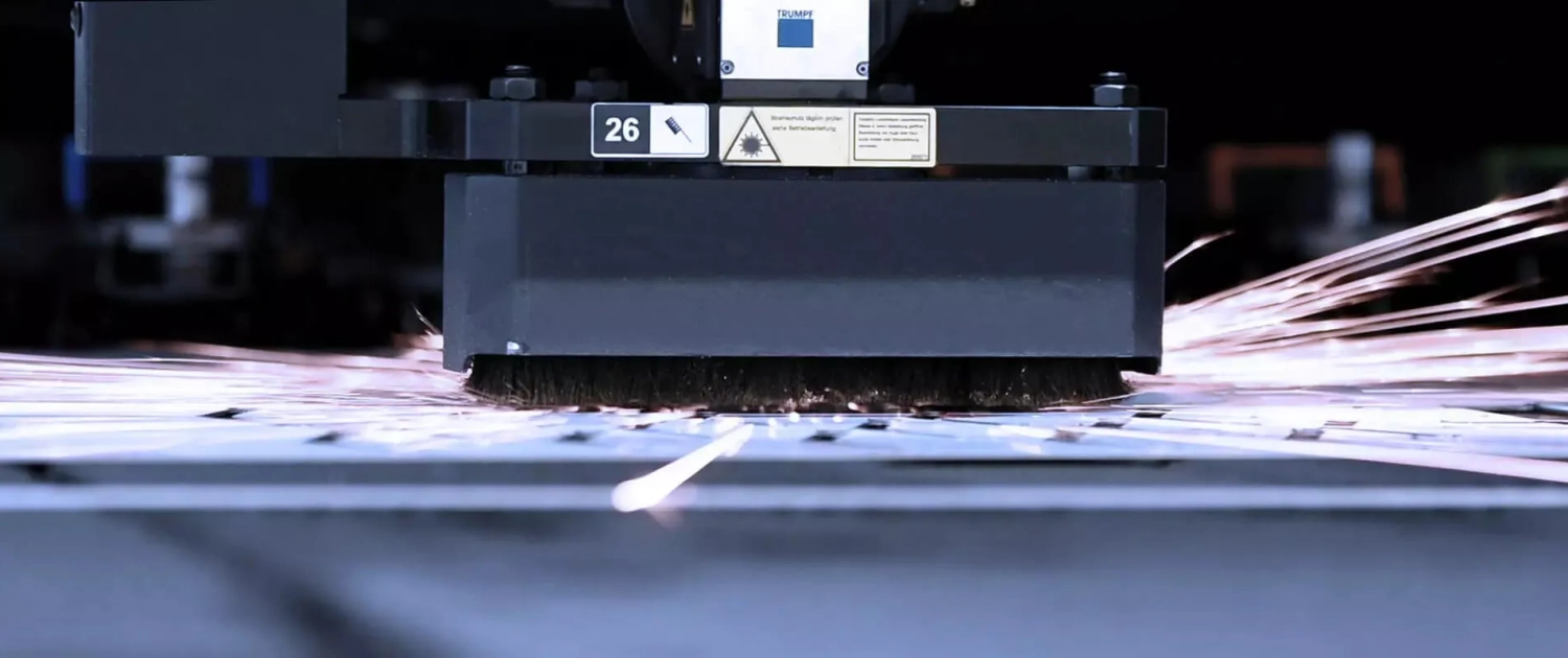 Headerbild für Webseite Prozesse Stanzen/Lasern, Laserkopf bearbeitet Blech mit Funken